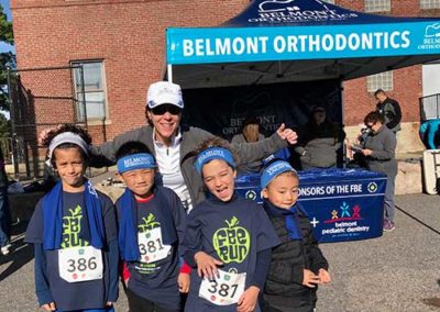 young kids standing together in front of Belmont Orthodontics Sponsor Tent
